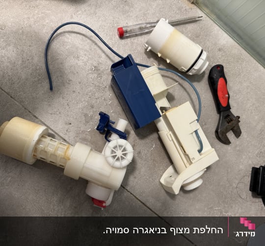 חלקי אינסטלציה וכלים על רצפה אפורה